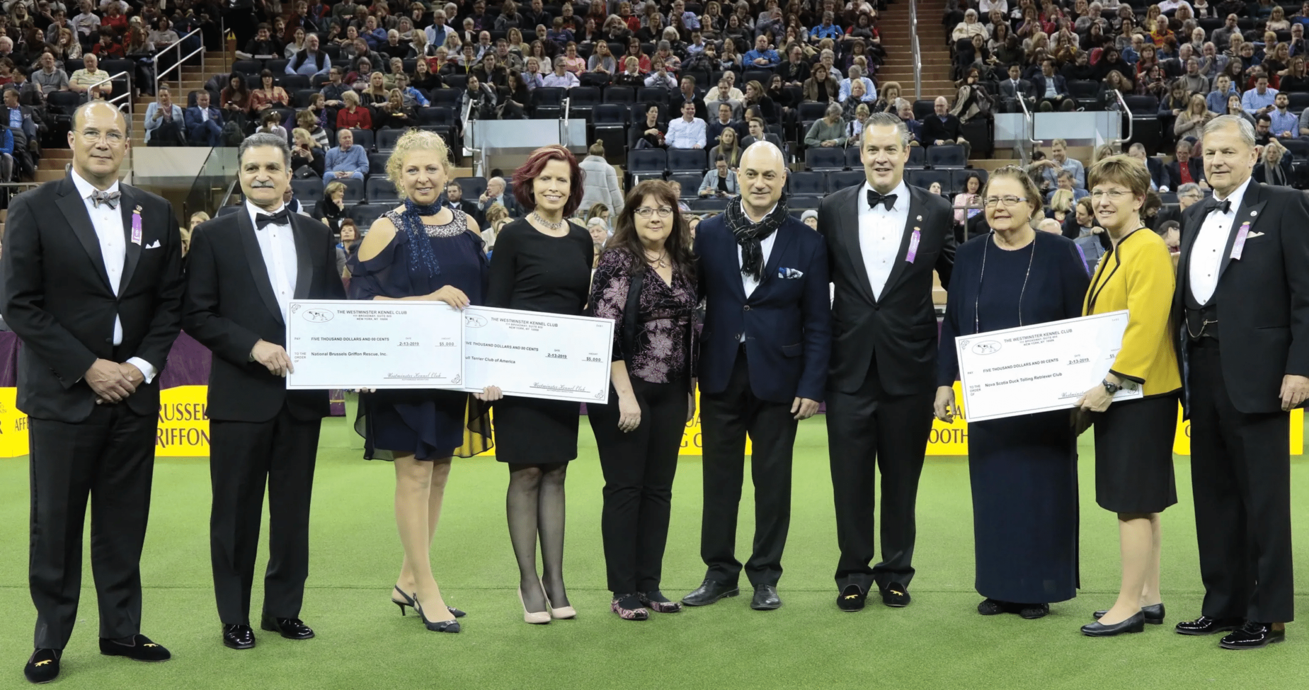 A group of people posing for a picture holding a check.