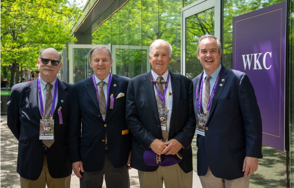 Four men in suits standing in front of a building, reminiscent of a scene from the Westminster Kennel Club.