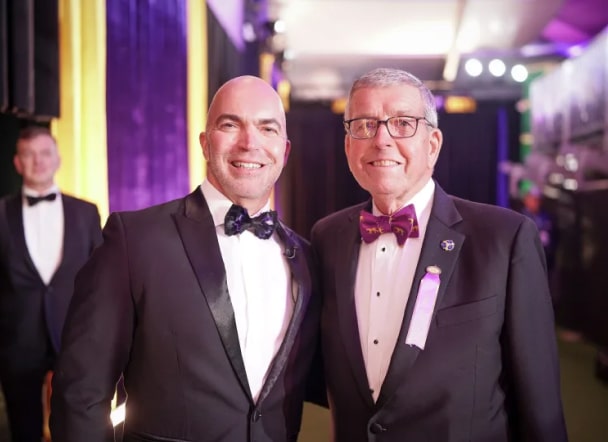 Two men in tuxedos standing next to each other.