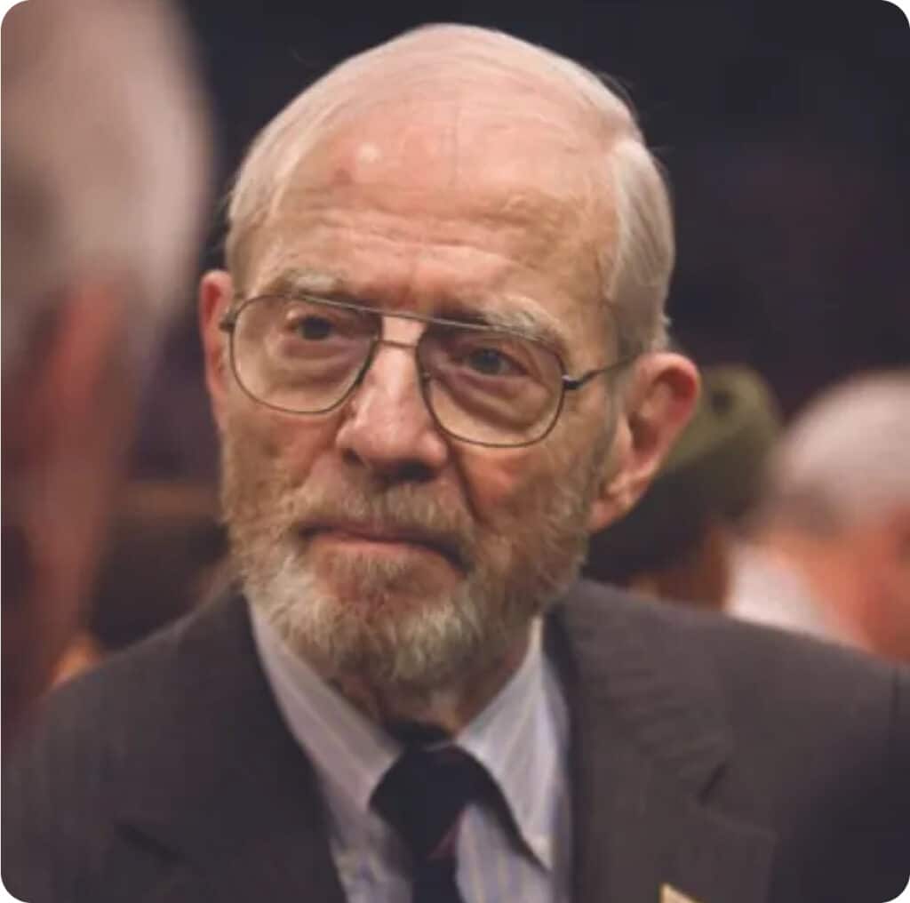 A close up of an older man with glasses and a beard.