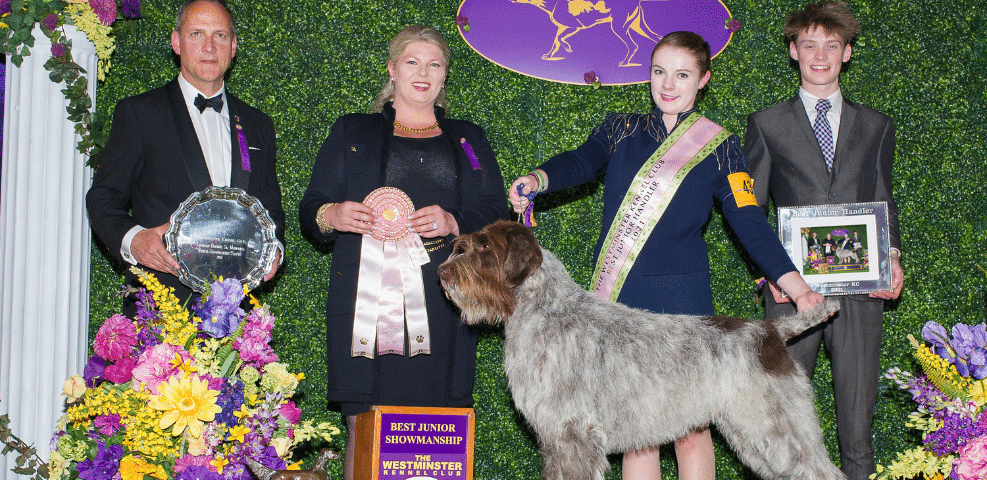 Award recipients posing with a prize-winning dog at a dog show event.
