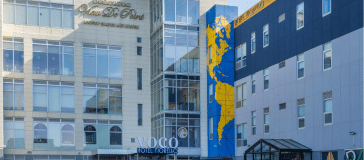 Urban street view showing a hotel with a large blue and yellow mural on the side of the building.