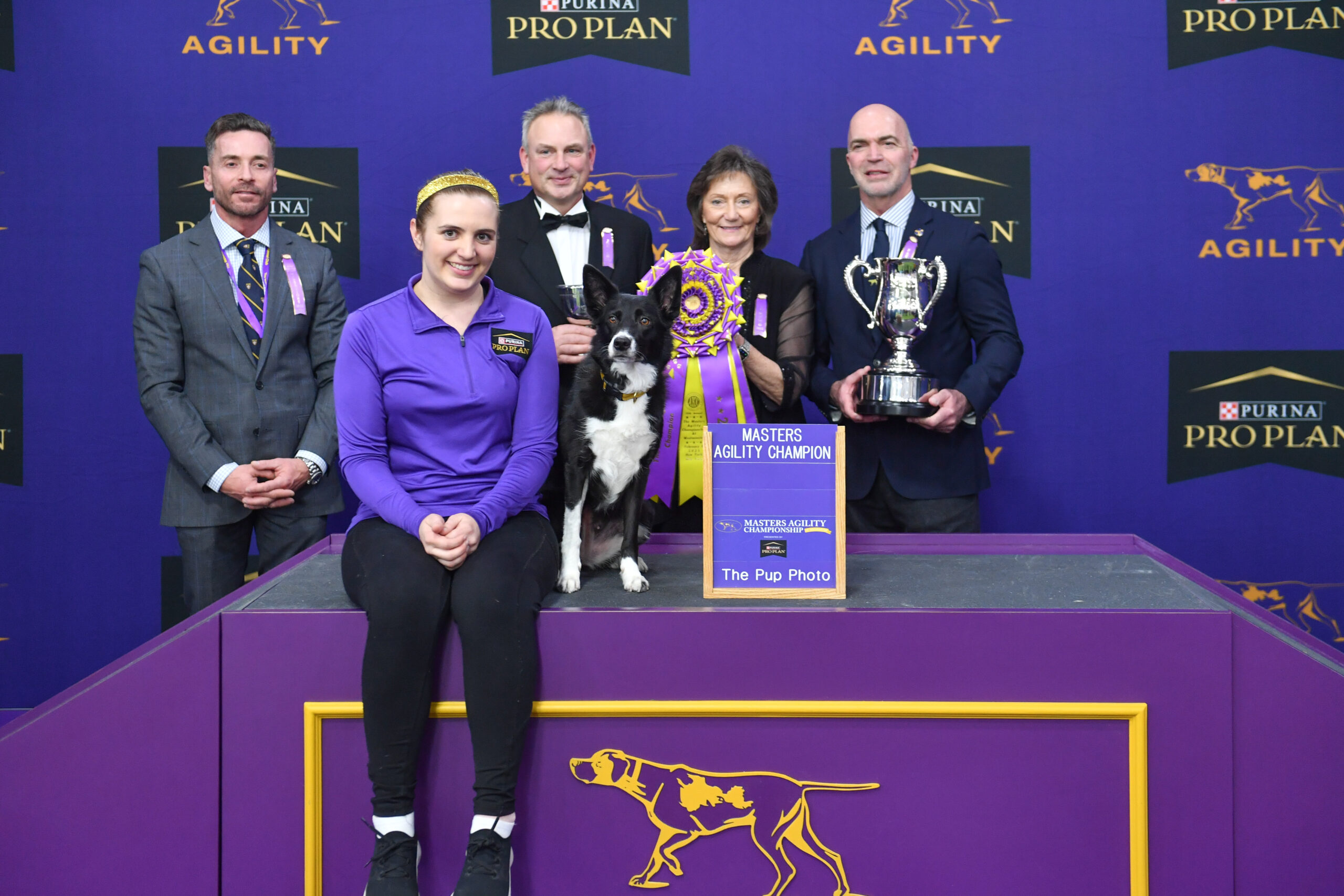 Five people pose with a black and white dog, a trophy, and ribbons at a Master’s Agility Champion event featuring Purina Pro Plan branding. Meet Dr. Sara Lyle: The Westminster Kennel Club’s 2025 Veterinarian of the Year.