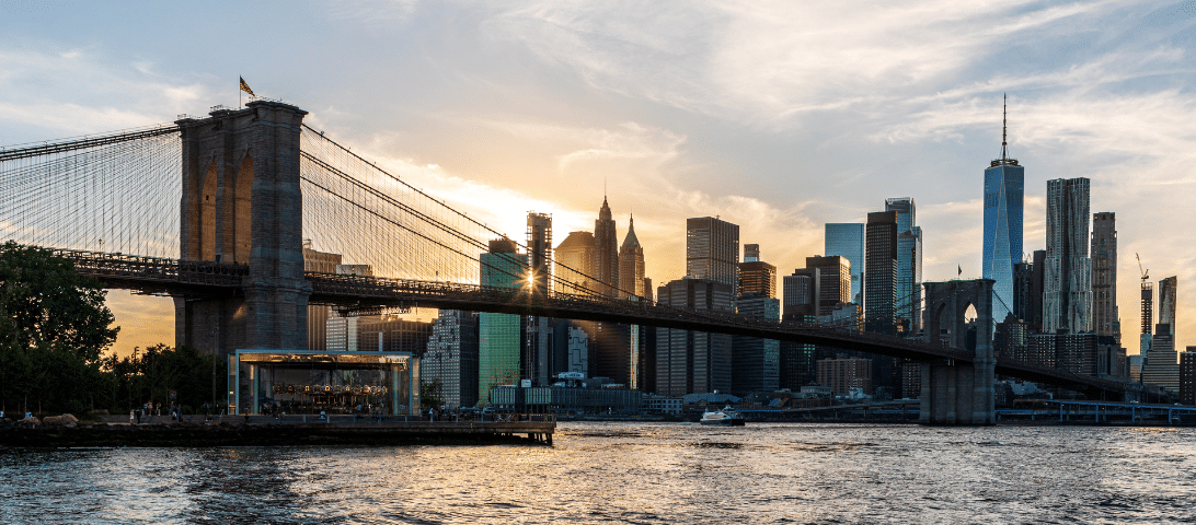 The Brooklyn Bridge spans the East River with the Manhattan skyline in the background at sunset, making it one of the top things to do when visiting New York City.