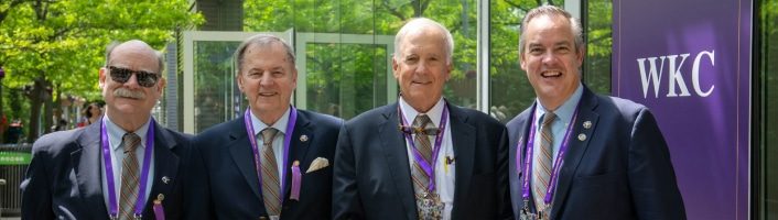 Four men in suits standing in front of a building at the Westminster Kennel Club.