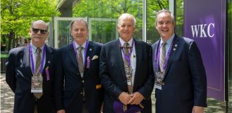 Four men in suits standing in front of a building, reminiscent of a scene from the Westminster Kennel Club.