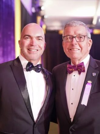 Two men in tuxedos standing next to each other.