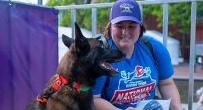 A woman with a dog in front of a fence.